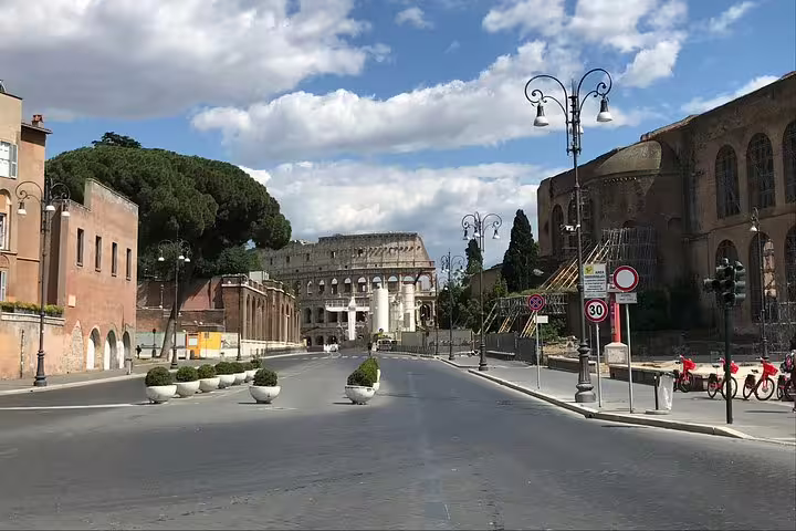 Empty Via Sacra street leading toward the Colosseum in ancient Rome on a sunny day