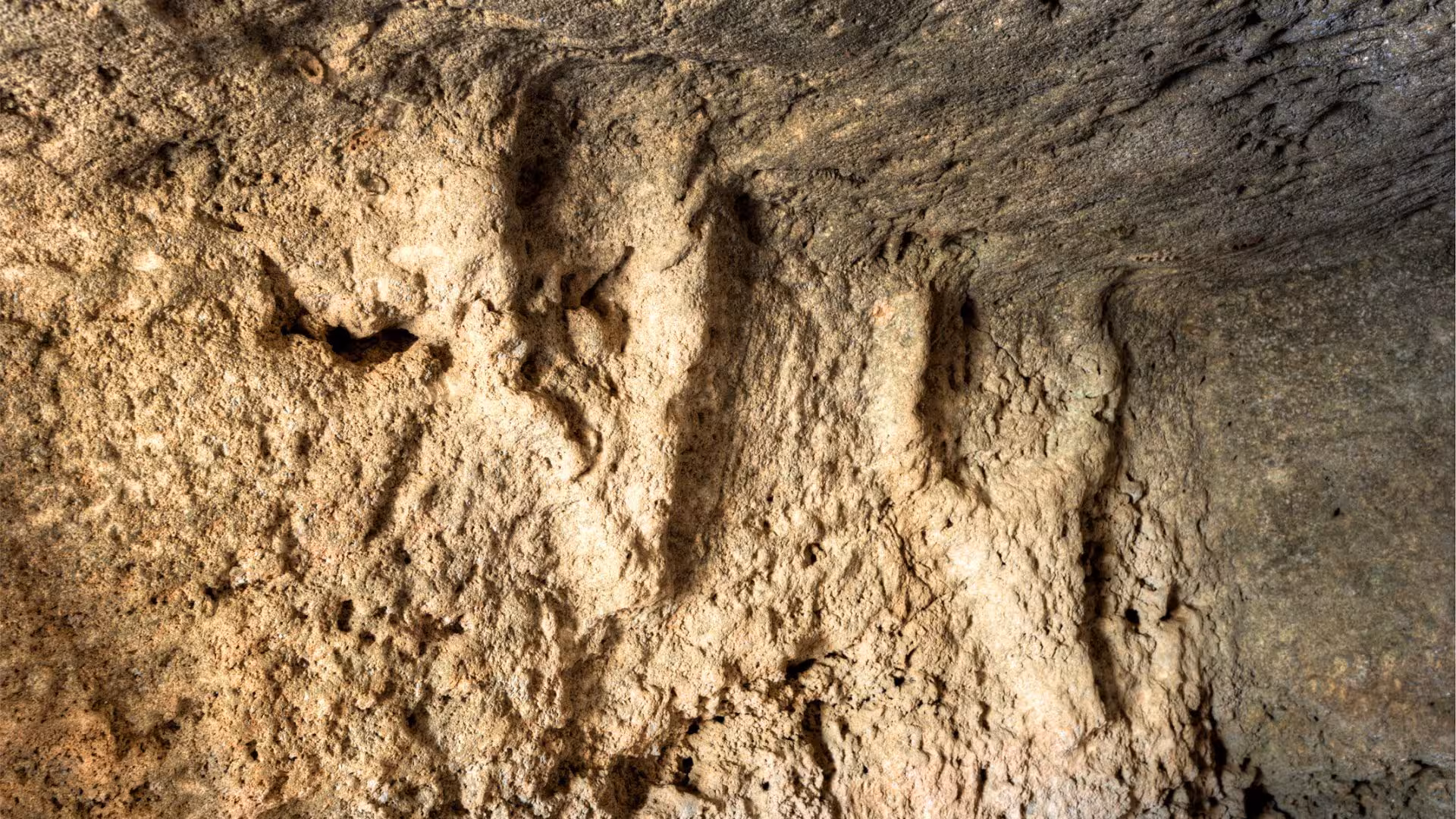 Explore the textured cave walls of Anghelu Ruju Necropolis in Alghero, showcasing ancient burial site details with audio guides.