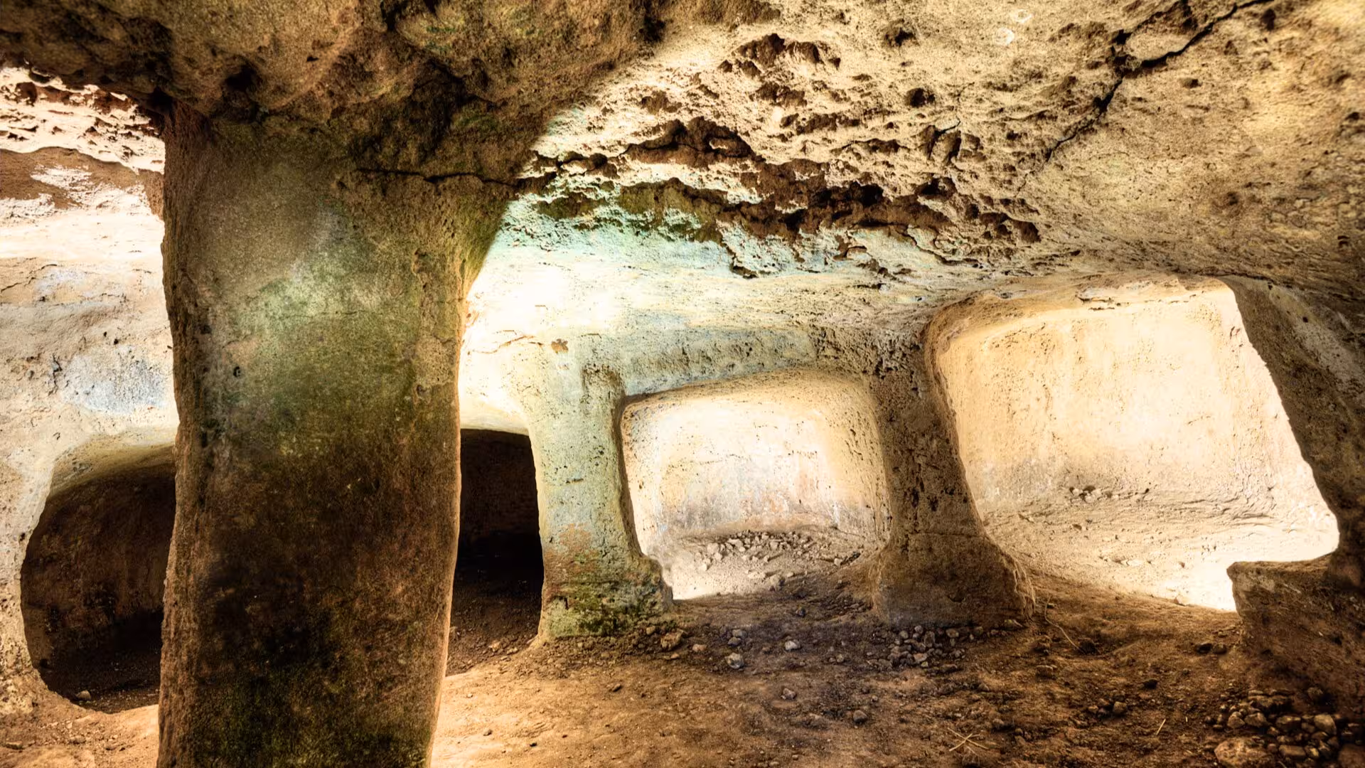 Venture into the intriguing chambers of Anghelu Ruju Necropolis, featuring ancient stone columns and rustic textures.