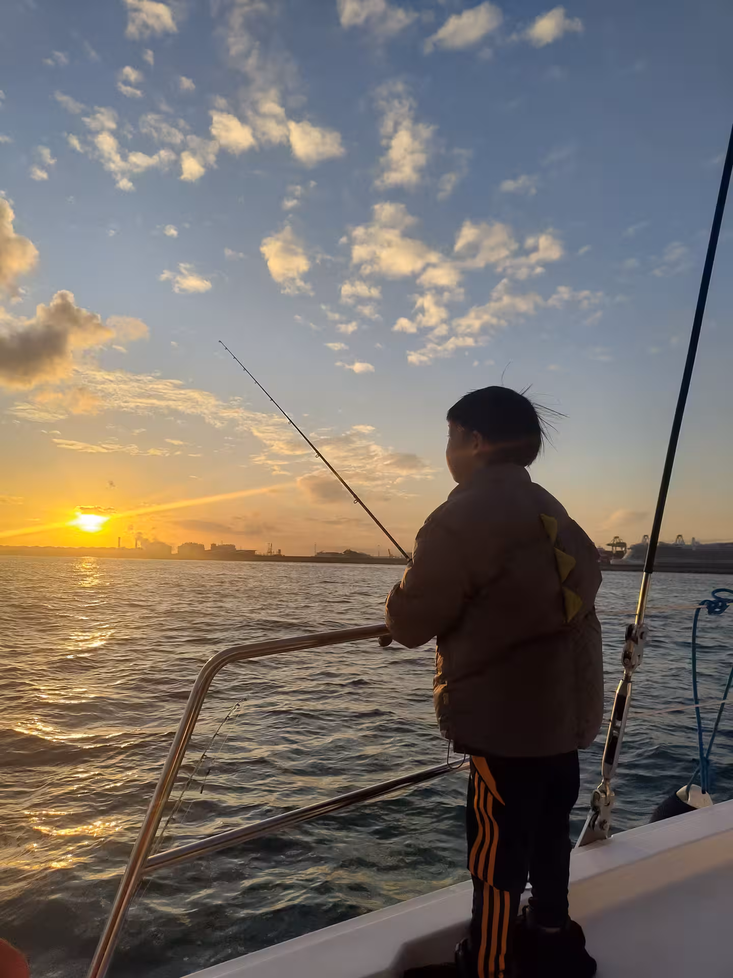 Angler casting line from boat at sunset on the Mediterranean Sea, guided fishing tour with scenic coastal views