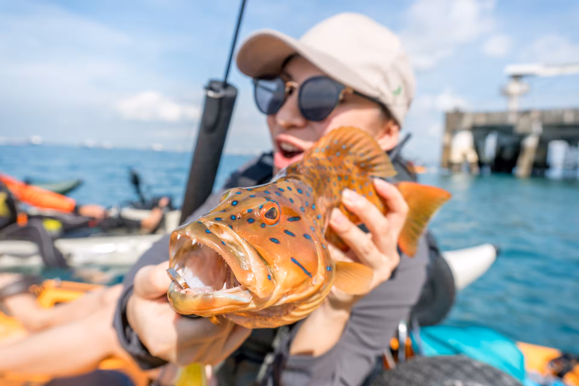 Excited angler holding a vibrant fish on a kayak during Saint John Island tour.