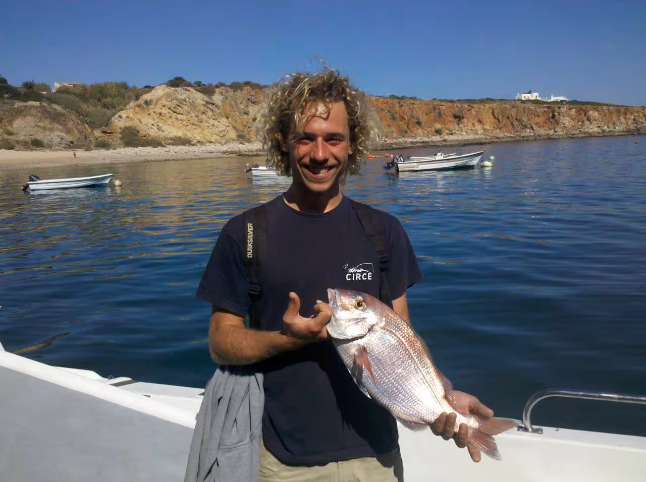 Happy angler proudly holding a freshly caught fish on a scenic boat trip, showcasing the excitement of sport fishing.