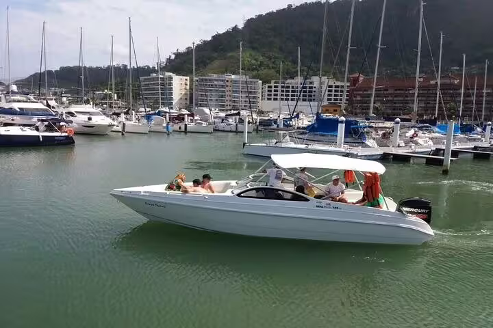Guests enjoying a boat tour in Angra dos Reis marina, surrounded by yachts and picturesque hills.