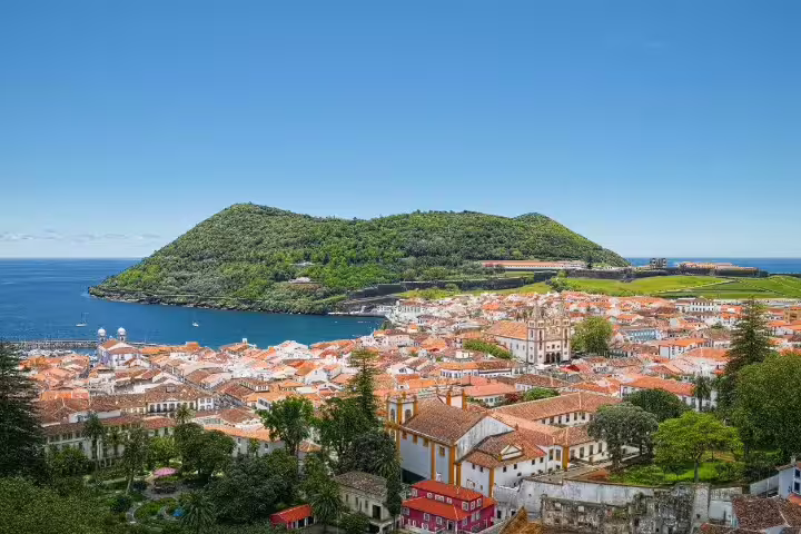 Aerial view of Angra do Heroísmo on Terceira Island, Azores, showcasing vibrant architecture and lush landscapes by the sea.
