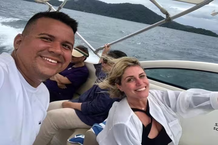 Smiling group enjoying a scenic boat tour on Angra & Ilha Grande with lush islands in the background.