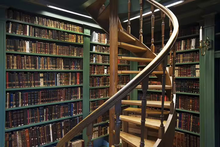 Spiral staircase amid historic bookshelves in Amsterdam's Jewish Cultural Quarter, featured in the Anne Frank Walking Tour.