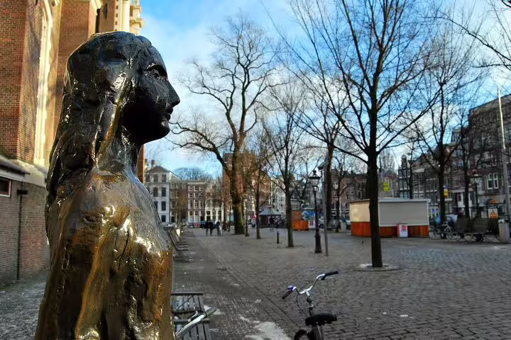 Bronze statue of Anne Frank beside Westerkerk in Amsterdam's Jordaan neighborhood on a sunny winter day