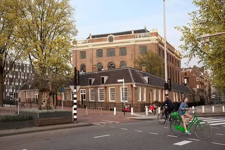 Historic building in Amsterdam's Jewish Cultural Quarter, a key stop on the Anne Frank Walking Tour, with cyclists passing by.