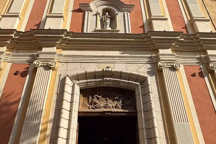 Baroque church facade with statue niche and ornate stone doorway in Antibes, French Riviera