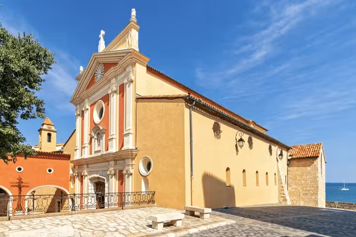 Baroque church facade with red and yellow walls in Antibes, French Riviera, overlooking the Mediterranean Sea