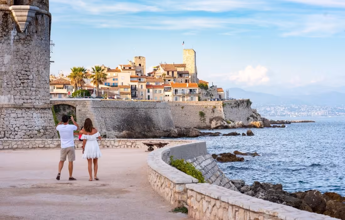 Couple admiring the old town ramparts and Mediterranean coastline of Antibes, French Riviera