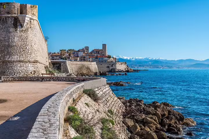 Ancient stone ramparts of Antibes old town along the Mediterranean coastline with snow-capped Alps in background