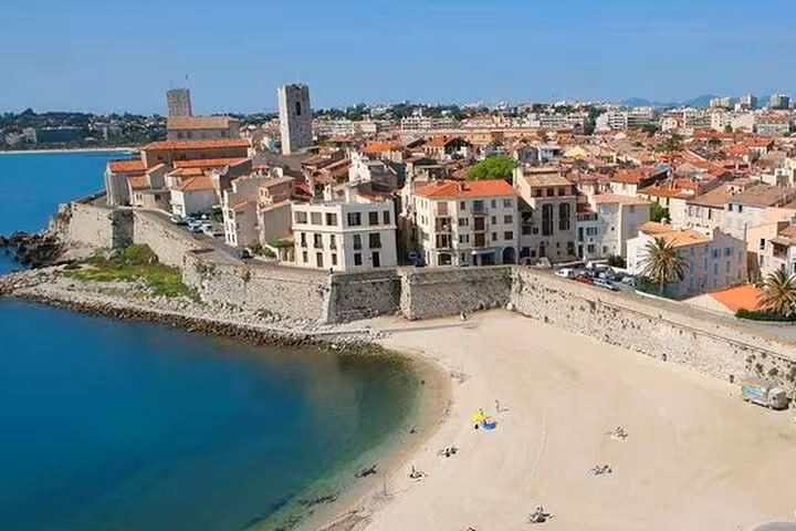 Aerial view of Antibes old town with medieval sea walls, sandy beach, and terracotta rooftops on the French Riviera