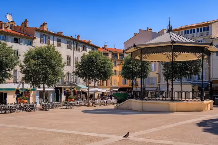 Sunny town square with ornate bandstand gazebo and café terraces in Antibes, France