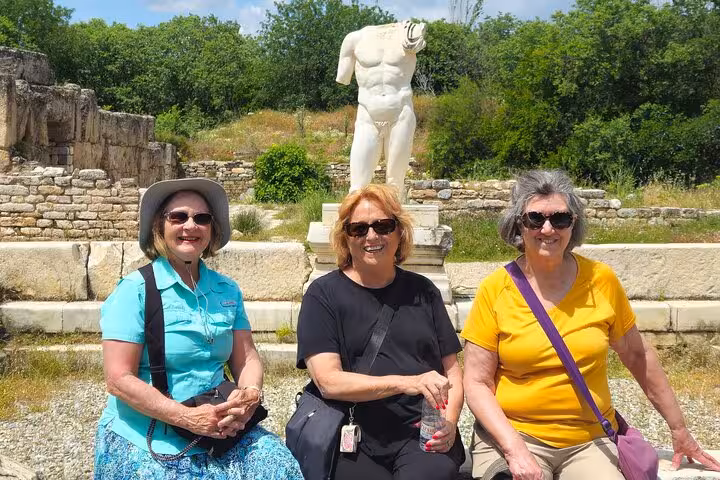 Visitors resting near a headless marble statue at Aphrodisias ruins on 2 day Ephesus Aphrodisias Pamukkale tour