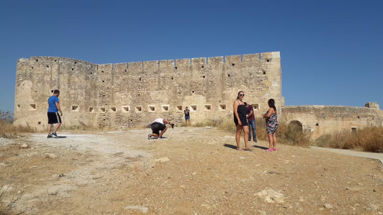 Tourists explore the ancient ruins of Aptera under a clear blue sky on the Explore Aptera & Chania tour.