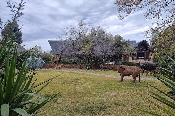 Sculpture-filled garden at Aquila Game Reserve lodge, ideal for a safari with transport and lunch included.