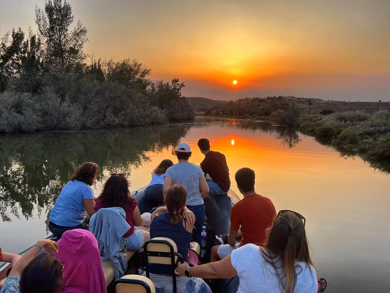 Friends relax on a private Arade River cruise at sunset, watching the sky reflect over tranquil waters on the way to Silves