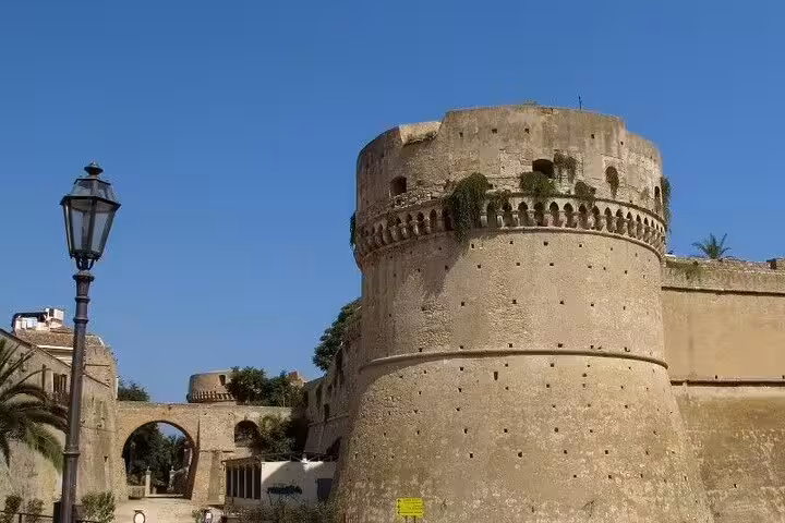 Historic stone tower and walls of Crotone’s Aragonese Castle under clear blue sky, visited on Isola Capo Rizzuto walking tour