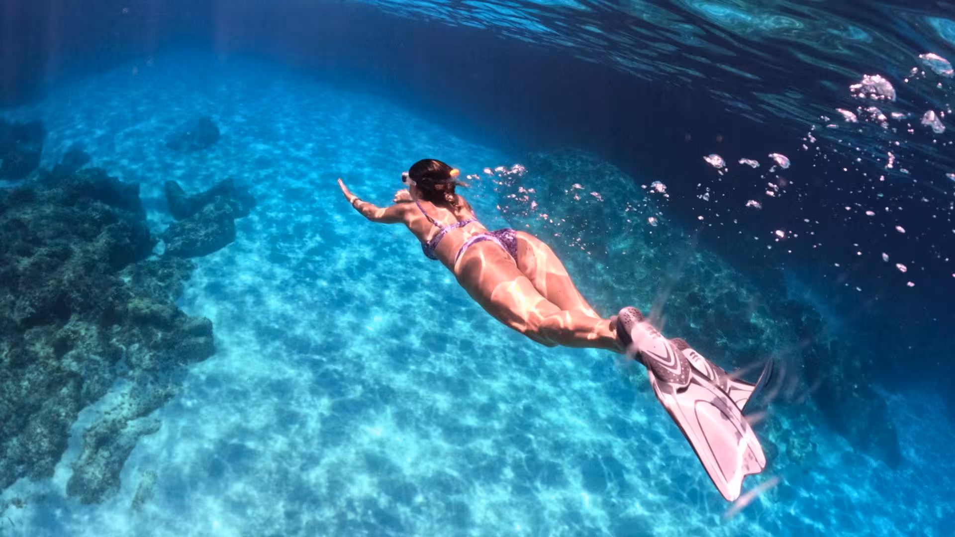 Snorkeler explores the crystal-clear waters of the Gulf of Orosei, unveiling vibrant marine life on a sailing trip.
