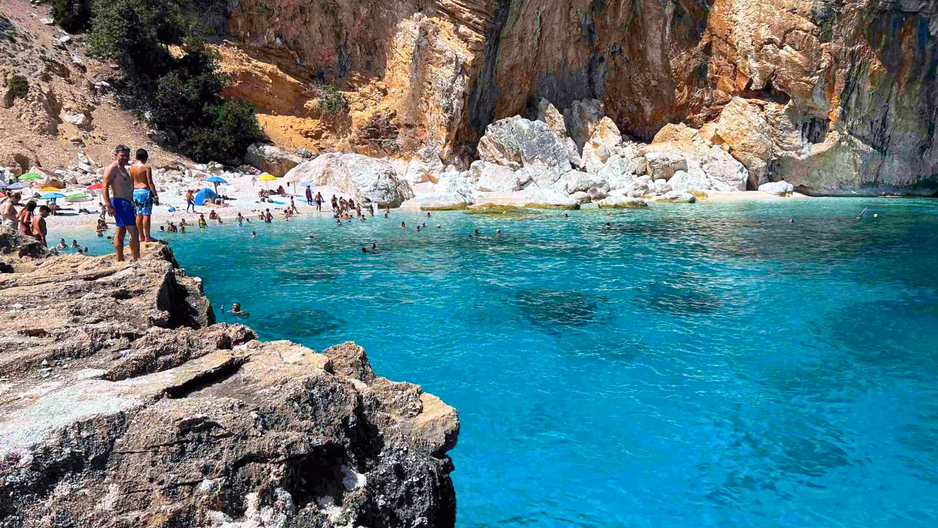 Tourists enjoy the turquoise waters and rugged cliffs of Cala Mariolu in the Gulf of Orosei, perfect for a sailing trip.
