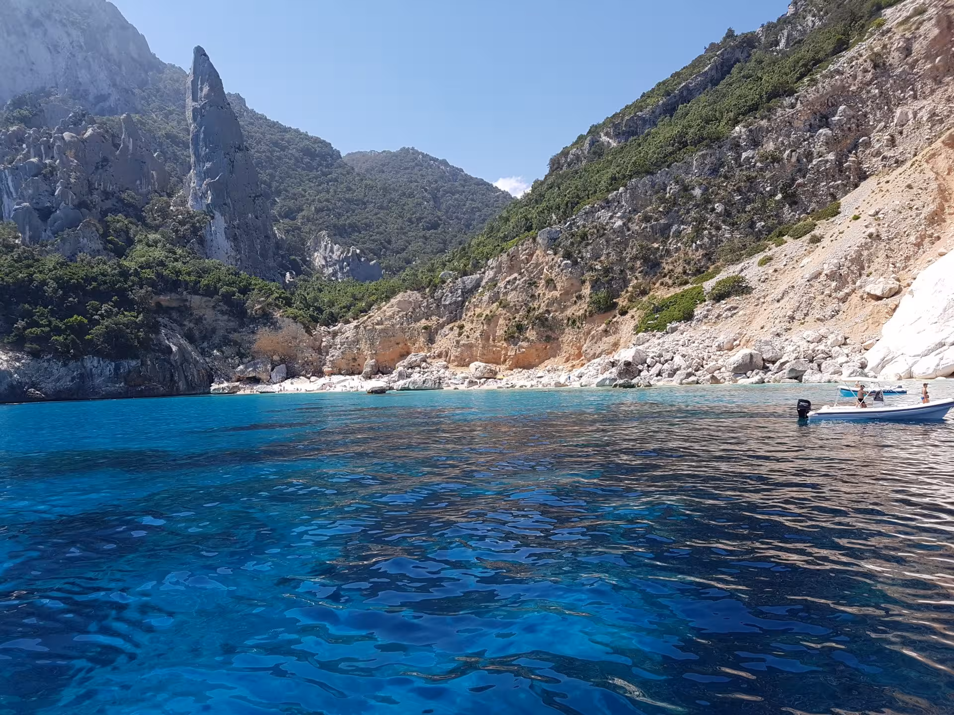 Vibrant turquoise waters and rocky cliffs at a secluded beach in the Gulf of Orosei, Sardinia.