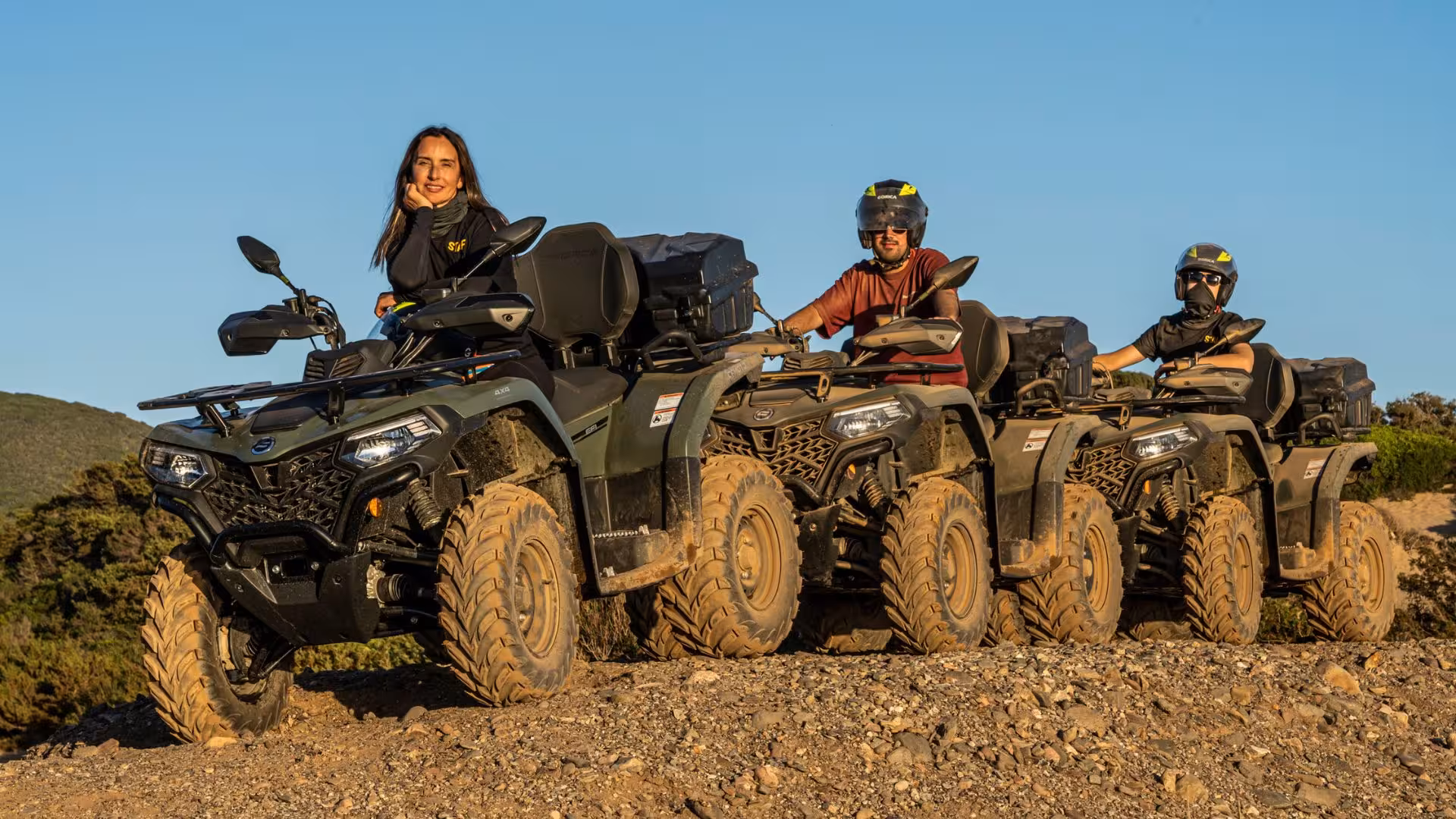 Smiling participants on ATVs ready for Arbus off-road adventure in the picturesque Costa Verde hills.