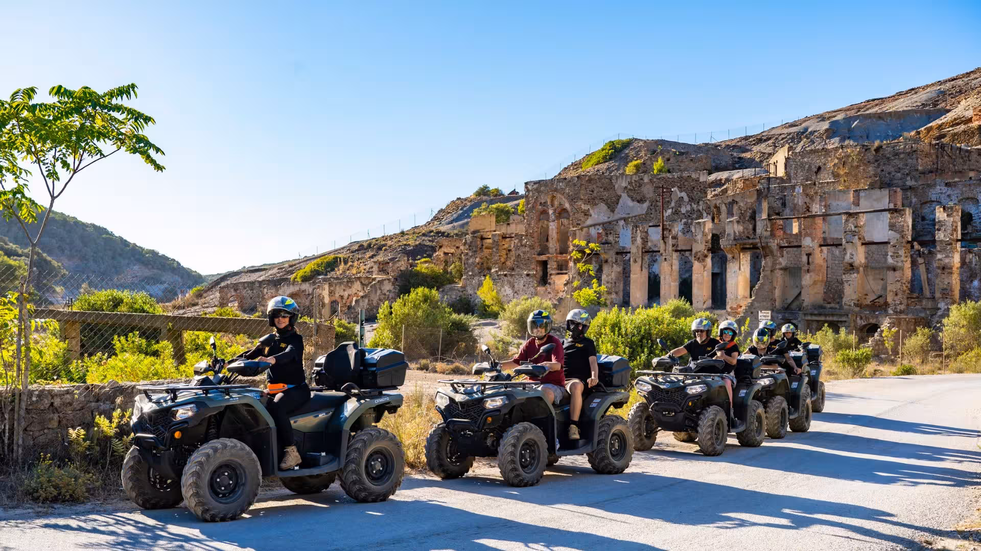 Group enjoying ATV excursion through historic Arbus mines and scenic landscapes under clear blue skies.