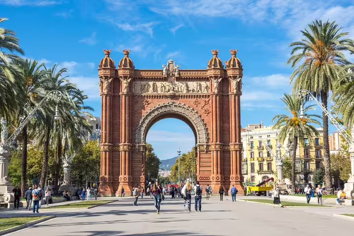 Arc de Triomf Barcelona with palm tree-lined promenade and tourists walking on sunny day