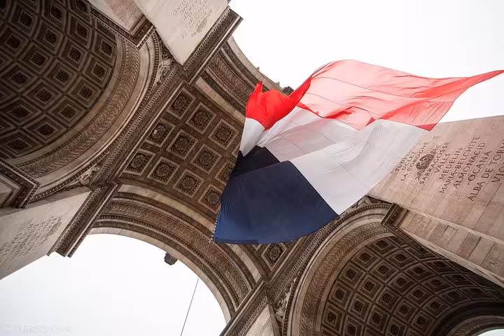 French flag under the Arc de Triomphe arch, highlight stop on a 2-hour private Champs-Élysées walk