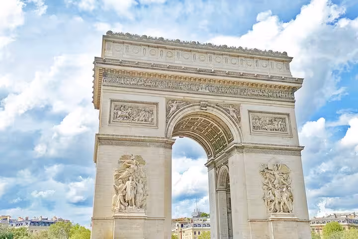 Arc de Triomphe monument with ornate sculptures and reliefs under a cloudy blue sky in Paris