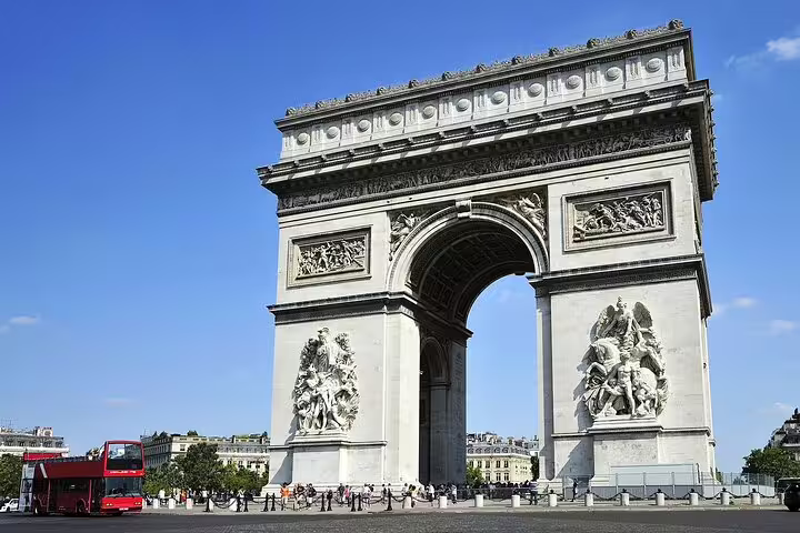 Arc de Triomphe with ornate stone carvings and a red double-decker bus in Paris, France