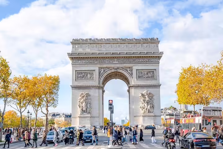 Arc de Triomphe with autumn trees and crowds crossing the street in Paris