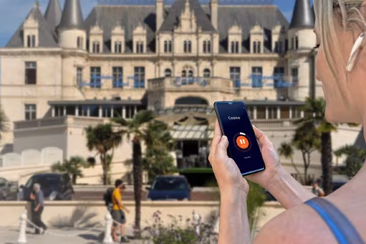 Woman holding smartphone with audio tour app in front of Arcachon Casino château