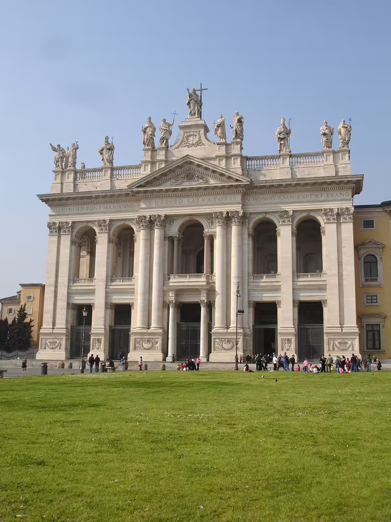 Exterior of Archbasilica of St John Lateran with statues and green lawn, stop on Christian Rome semi-private tour