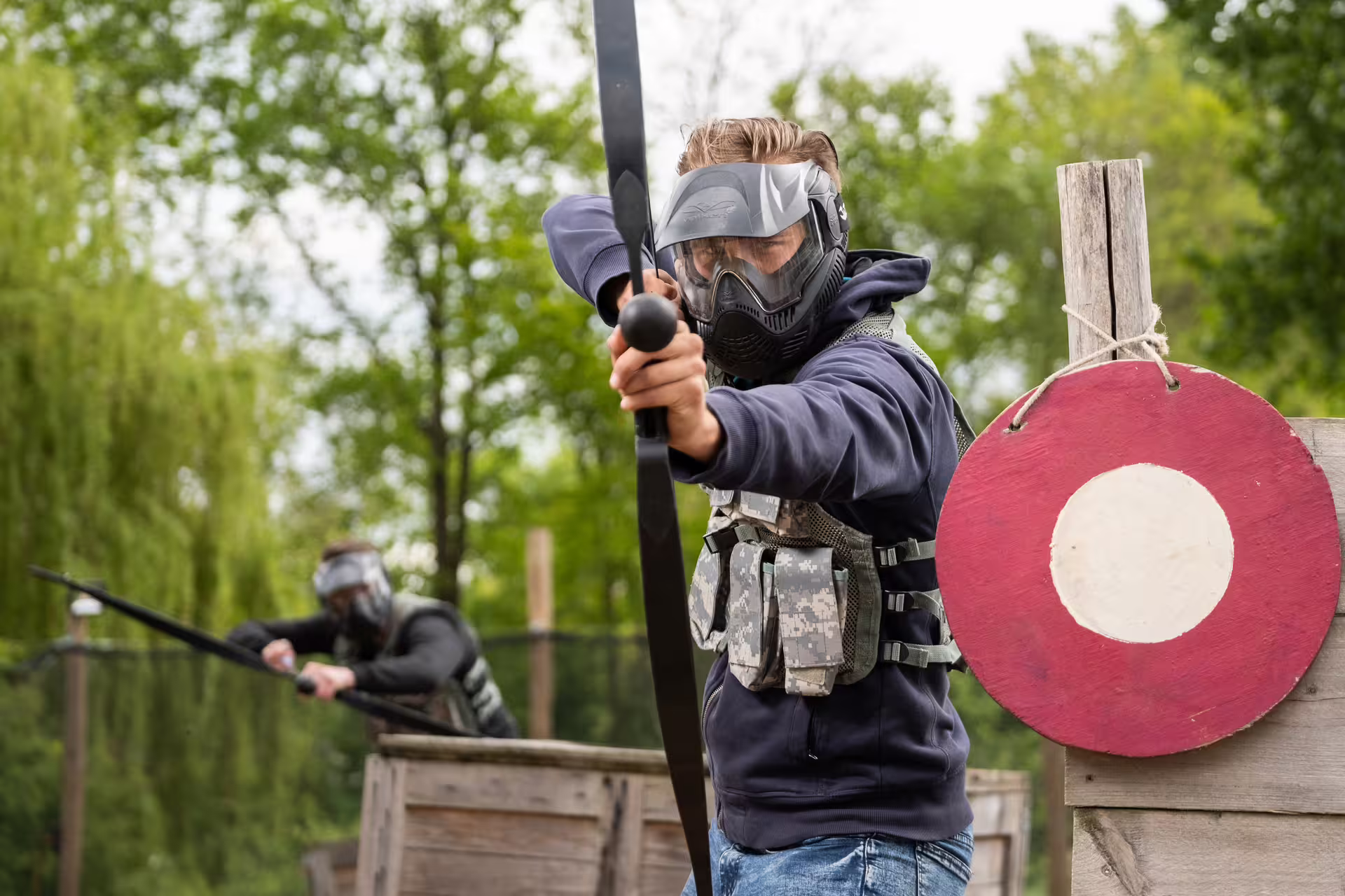 Player in mask aims bow during archery tag in Amsterdam, action-packed team game for friends and corporate groups