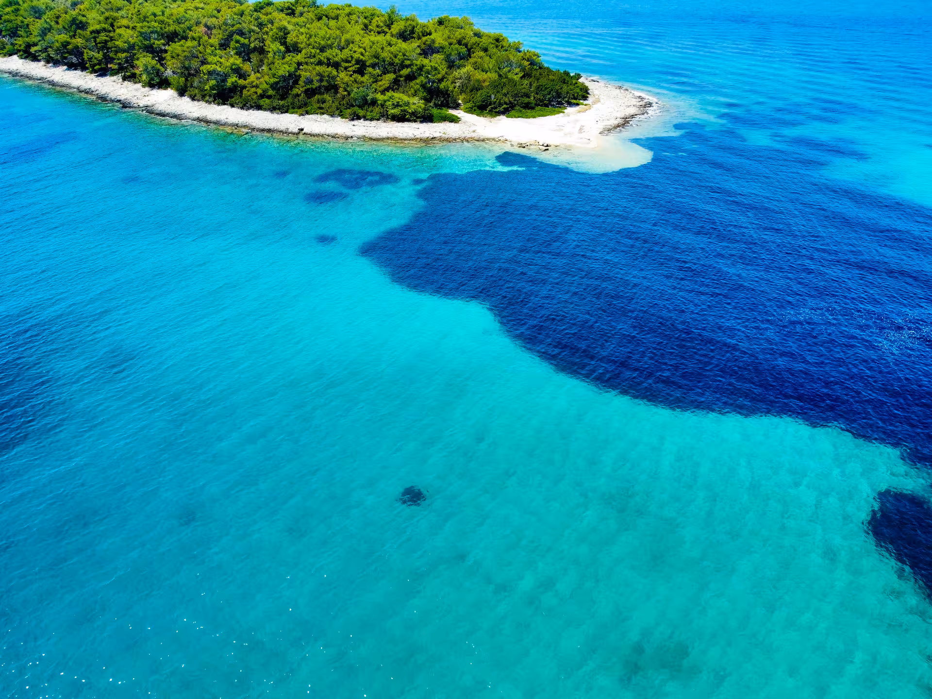 Drone shot of secluded islet and crystal-clear shallows, Archipelago Adventure island-hopping cruise