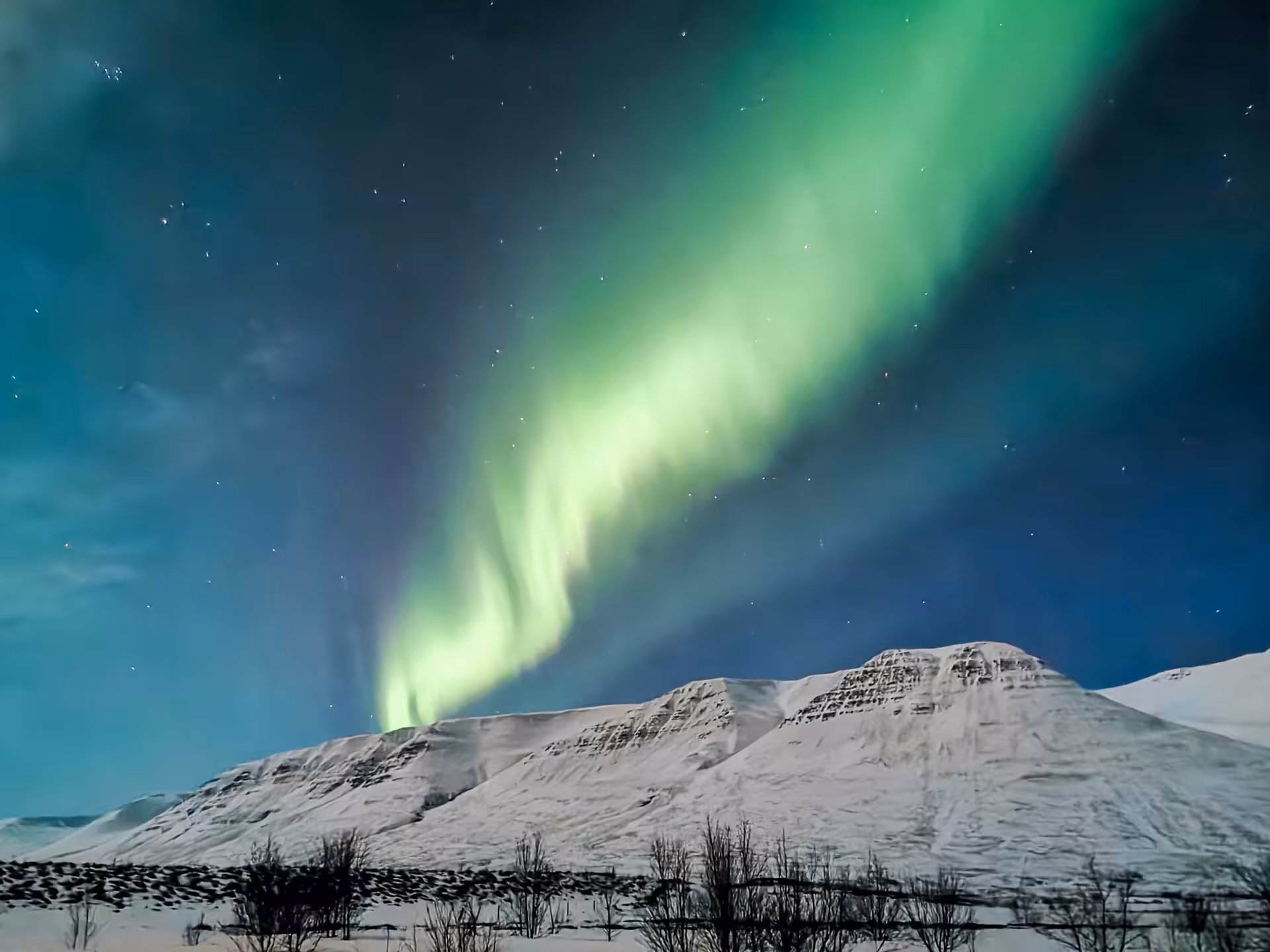Northern Lights over snowy Arctic mountains on a private husky adventure, Arctic Odyssey aurora tour