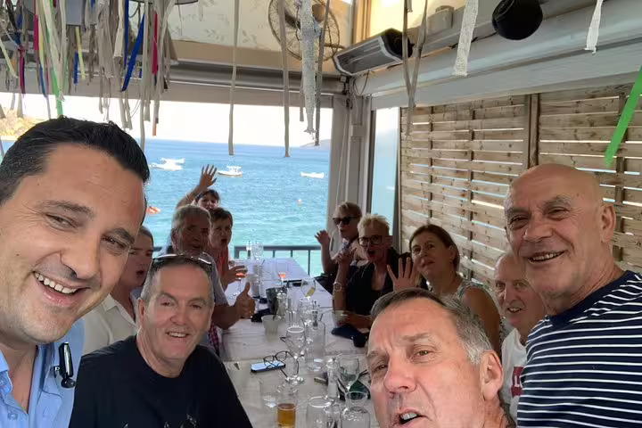 Group enjoying seaside taverna lunch with Aegean view during Argolis private full-day tour from Athens