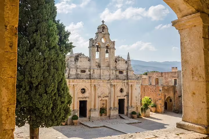 Visit the iconic Arkadi Monastery, featuring its stunning facade framed by lush greenery and mountain views.