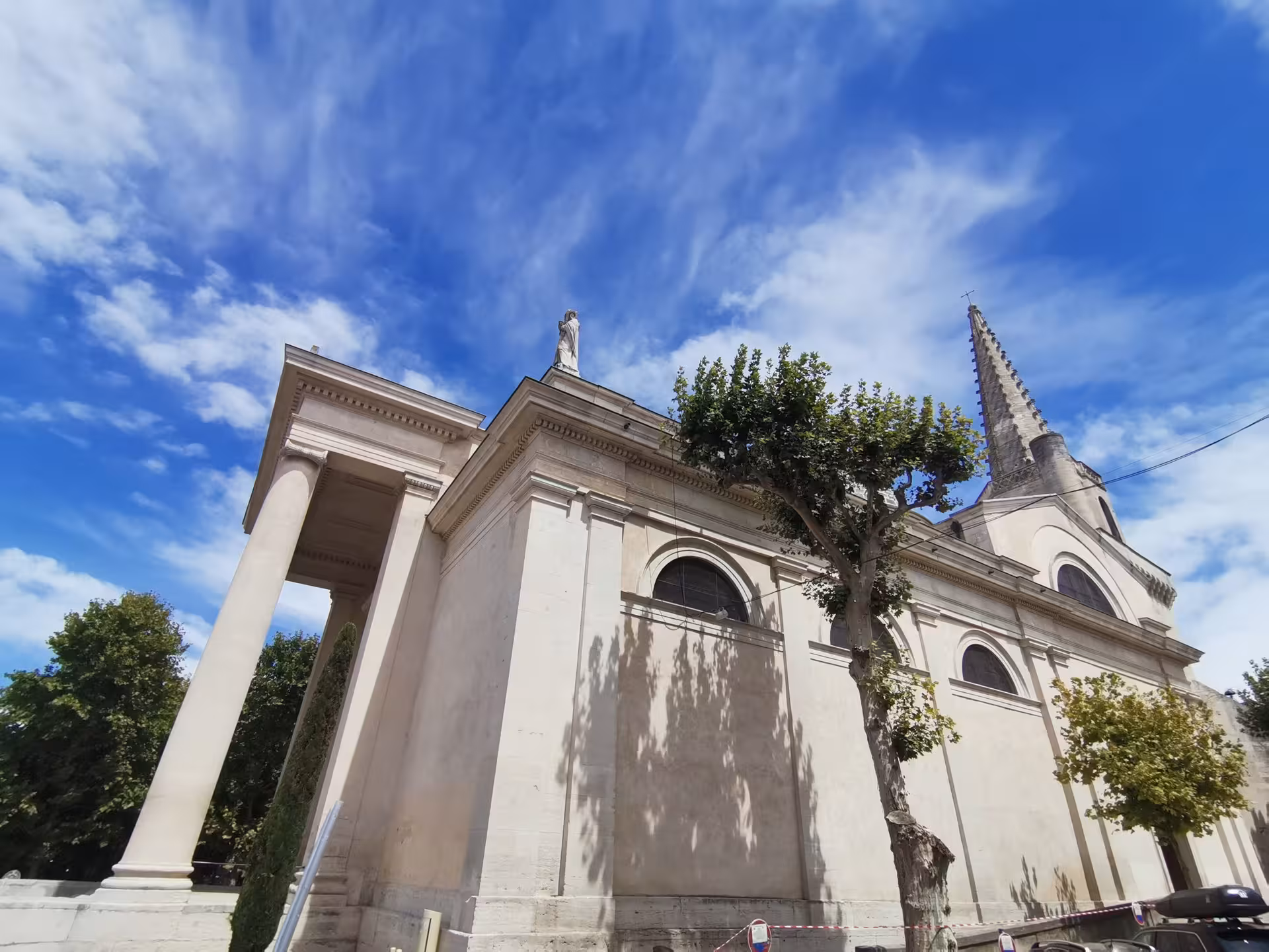 Church facade and spire in Arles Provence under blue sky, a highlight of Les Baux day tour