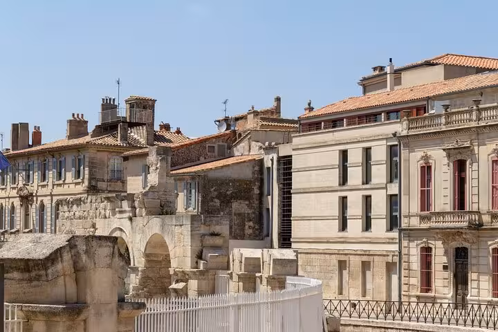 Charming Arles cityscape with historic Roman architecture and modern buildings under a clear blue sky.