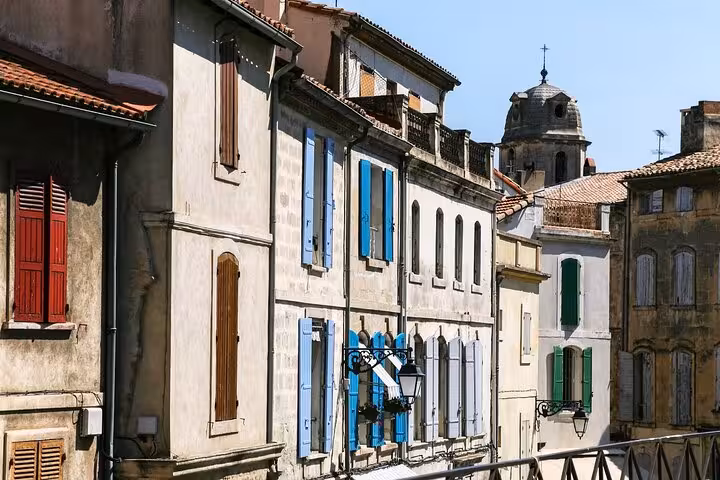 Charming street view in Arles with colorful shutters and historic architecture on a sunny day.