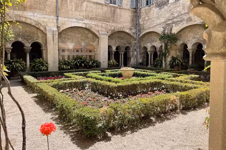 Romanesque cloister garden in Arles with arched stone corridors and manicured hedges on a private day trip