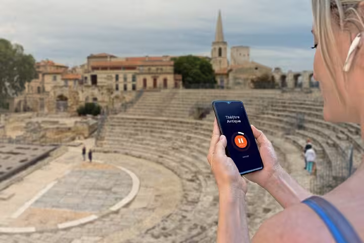 Tourist using audio guide app at Théâtre Antique ruins in Arles, France