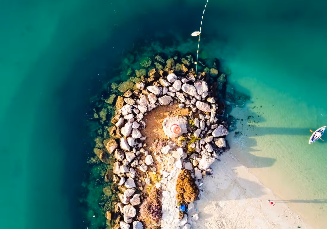 Aerial drone view of rocky outcrop with turquoise waters near Armona Island on a scenic Ria Formosa boat tour