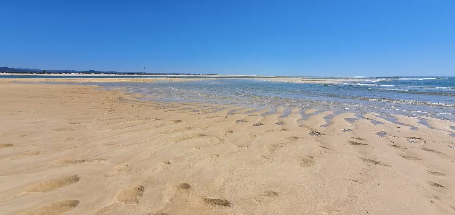Expansive sandy beach on Armona Island with clear blue skies and gentle waves, perfect for a serene getaway.