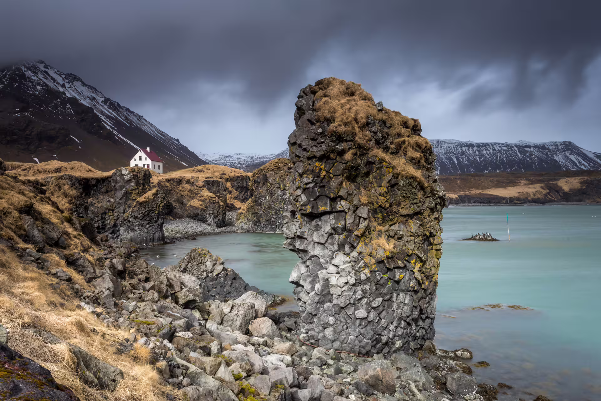 Arnarklettur sea rock with the house Arnarstapi in the background