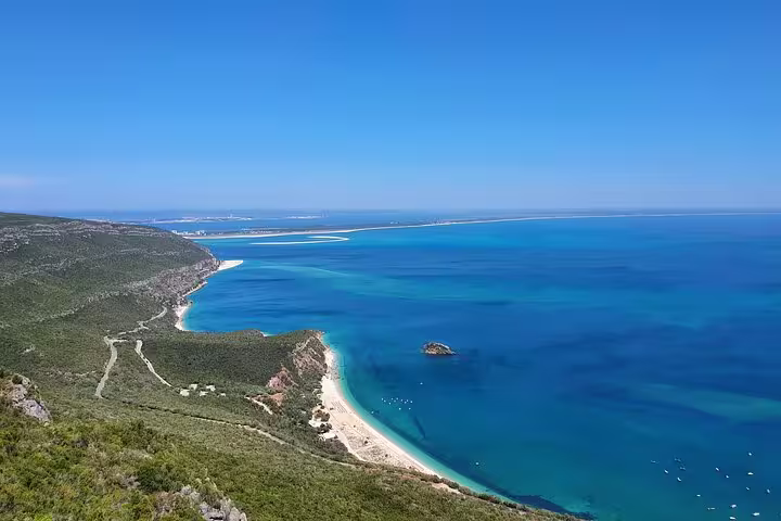 Scenic view of Arrábida's stunning coastline with turquoise waters and lush greenery, perfect for a Lisbon day tour adventure.