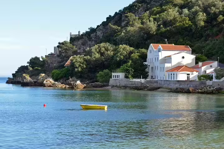 Scenic view of Arrábida coastline with a yellow boat on tranquil waters, perfect for a private tour with wine tasting in Sesimbra and Setúbal.